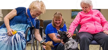 three women smiling and petting a dog